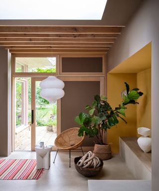 light and open living space with yellow accent wall, brown wall, wood ceiling beams and boho decor