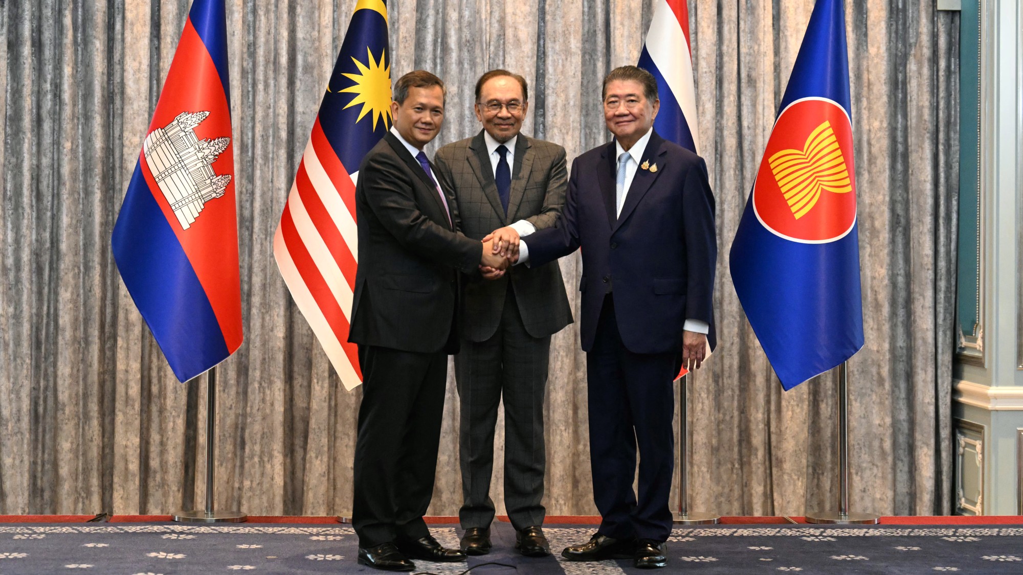 Malaysia's Prime Minister Anwar Ibrahim (C), Cambodia's Prime Minister Hun Manet (L) and Thailand's acting Prime Minister Phumtham Wechayachai (R) pose for photos as they shake hands