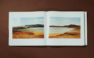 Double page photo of a landscape that features a large lake and cliffs. .
