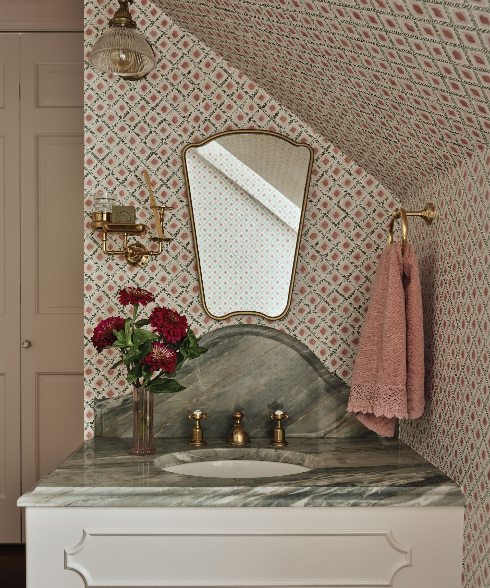 a pink pattern drenched guest bathroom with small vanity with marble top