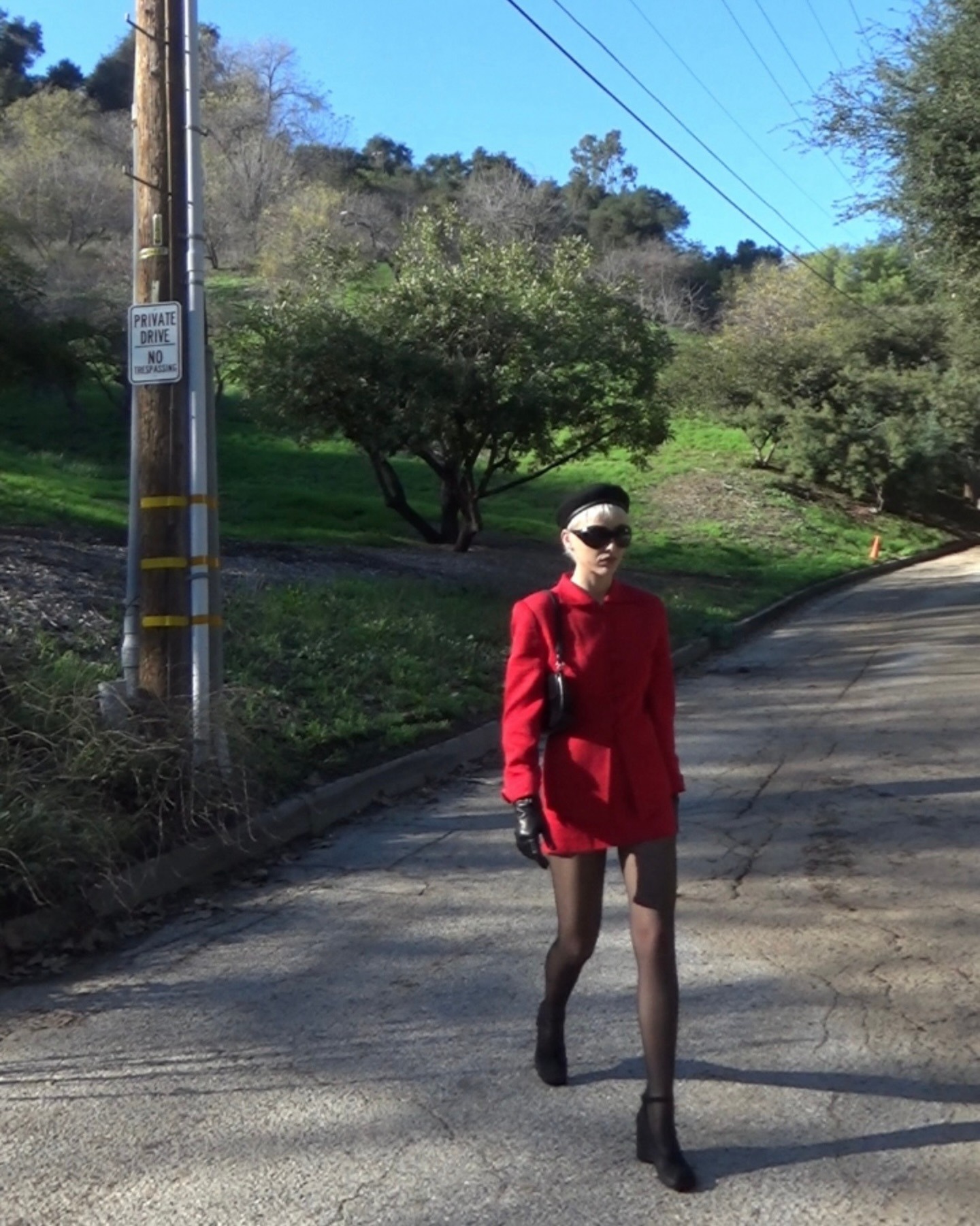 Emma Chamberlin wears a red skirt suit with wedges, heels a beret and a black bag.