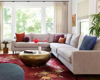 A living room with grey sofa, red rug and bright colored cushions