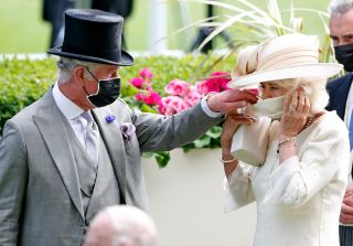 ASCOT, UNITED KINGDOM - JUNE 16: (EMBARGOED FOR PUBLICATION IN UK NEWSPAPERS UNTIL 24 HOURS AFTER CREATE DATE AND TIME) Prince Charles, Prince of Wales helps Camilla, Duchess of Cornwall put on her face mask as they attend day 2 of Royal Ascot at Ascot Racecourse on June 16, 2021 in Ascot, England. (Photo by Max Mumby/Indigo/Getty Images)