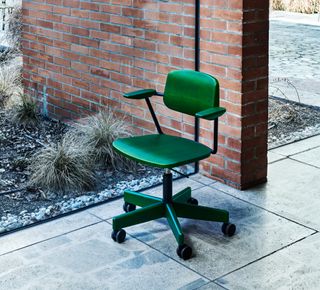 A vivid green office chair photographed in the front yard of the house.