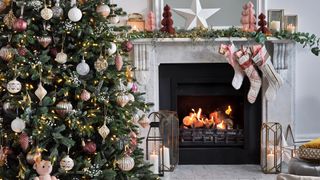 Living room with christmas tree decorated with pink baubles and matching stocking hanging on the mantel to show a color coordinated christmas decorating idea