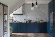 Small blue kitchen with grey tiled splashback and no wall cabinets
