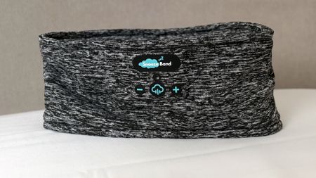 A closeup of the SnoozeBand Original Sleep headband standing upright on a pillow in our reviewer's bedroom