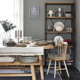 Green dining room with tall industrial style shelving unit and table dressed for Christmas