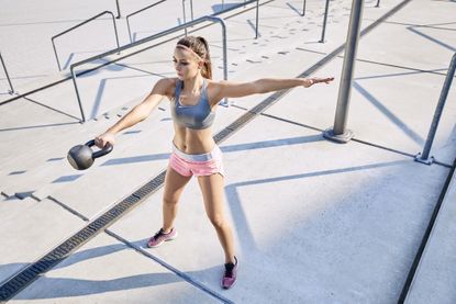 Woman doing a single-hand kettlebell swing.