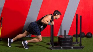 Man pushes a weighted sled in a gym