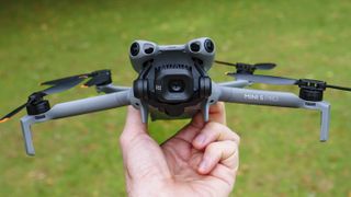 DJI Mini 5 Pro in pilot's hand, grass background