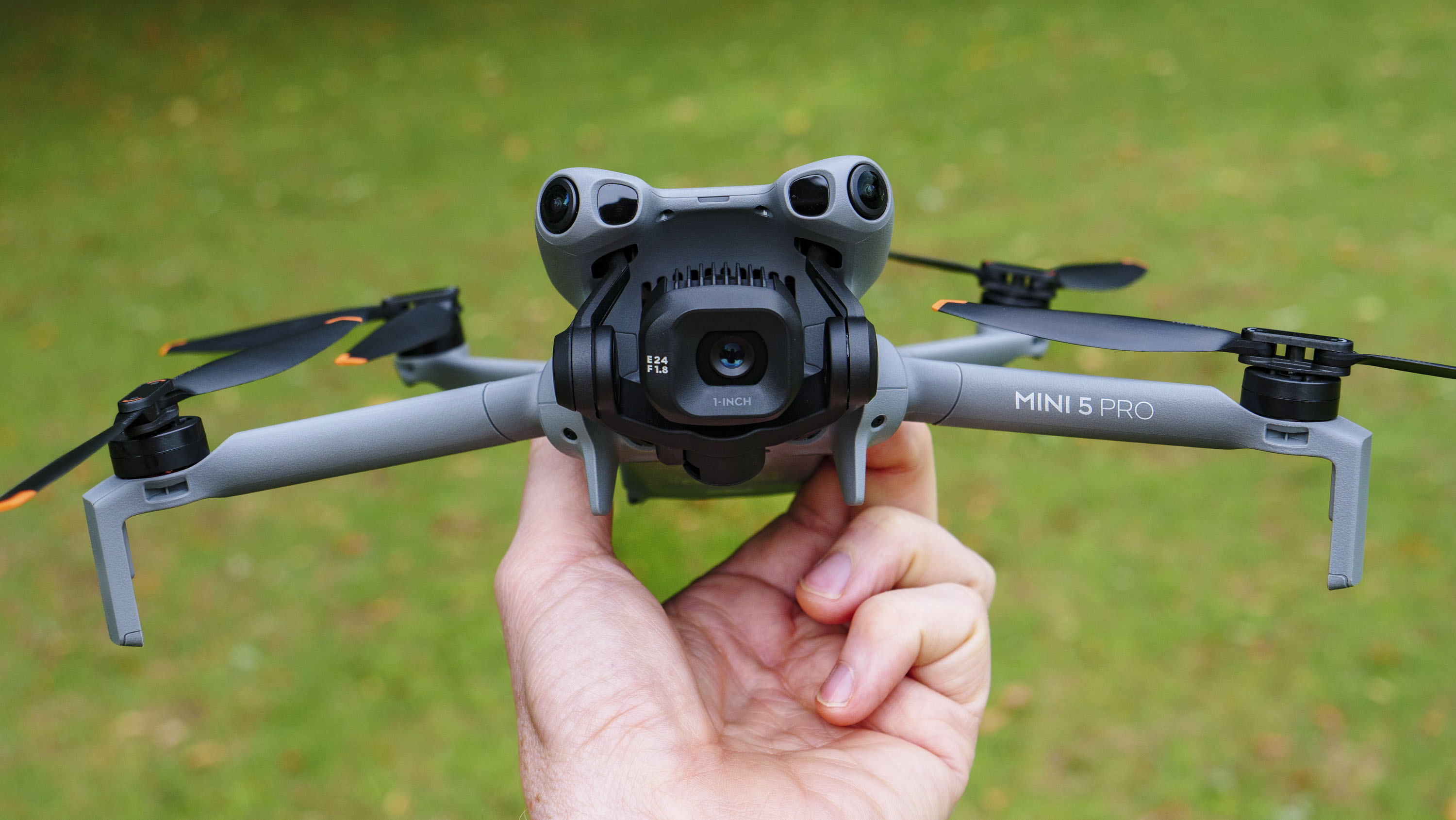 DJI Mini 5 Pro in pilot's hand, grass background