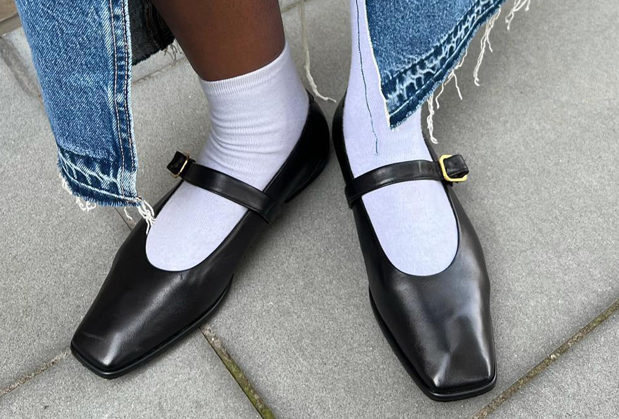 Woman wearing black Mary Jane flats with white sock and denim skirt.