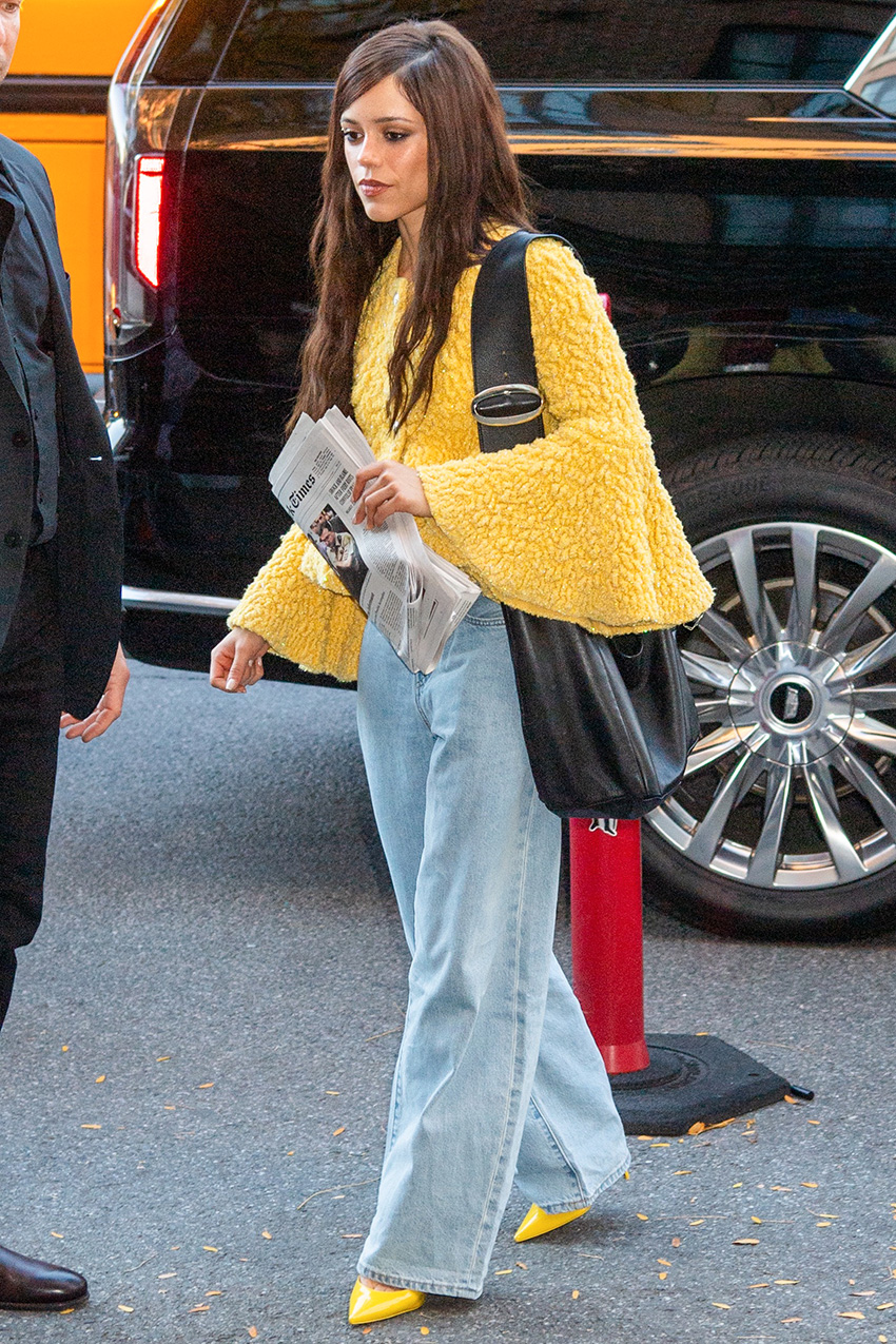 Jenna Ortega wearing jeans, a yellow sweater, and matching yellow pumps.