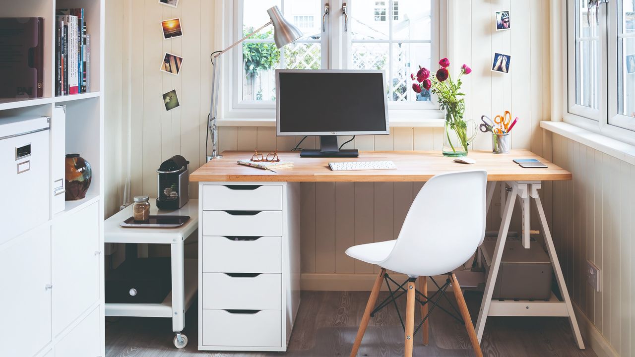 A home office with a desk and a large window