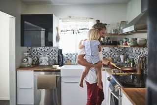 dad holding his toddler while cooking in the kitchen