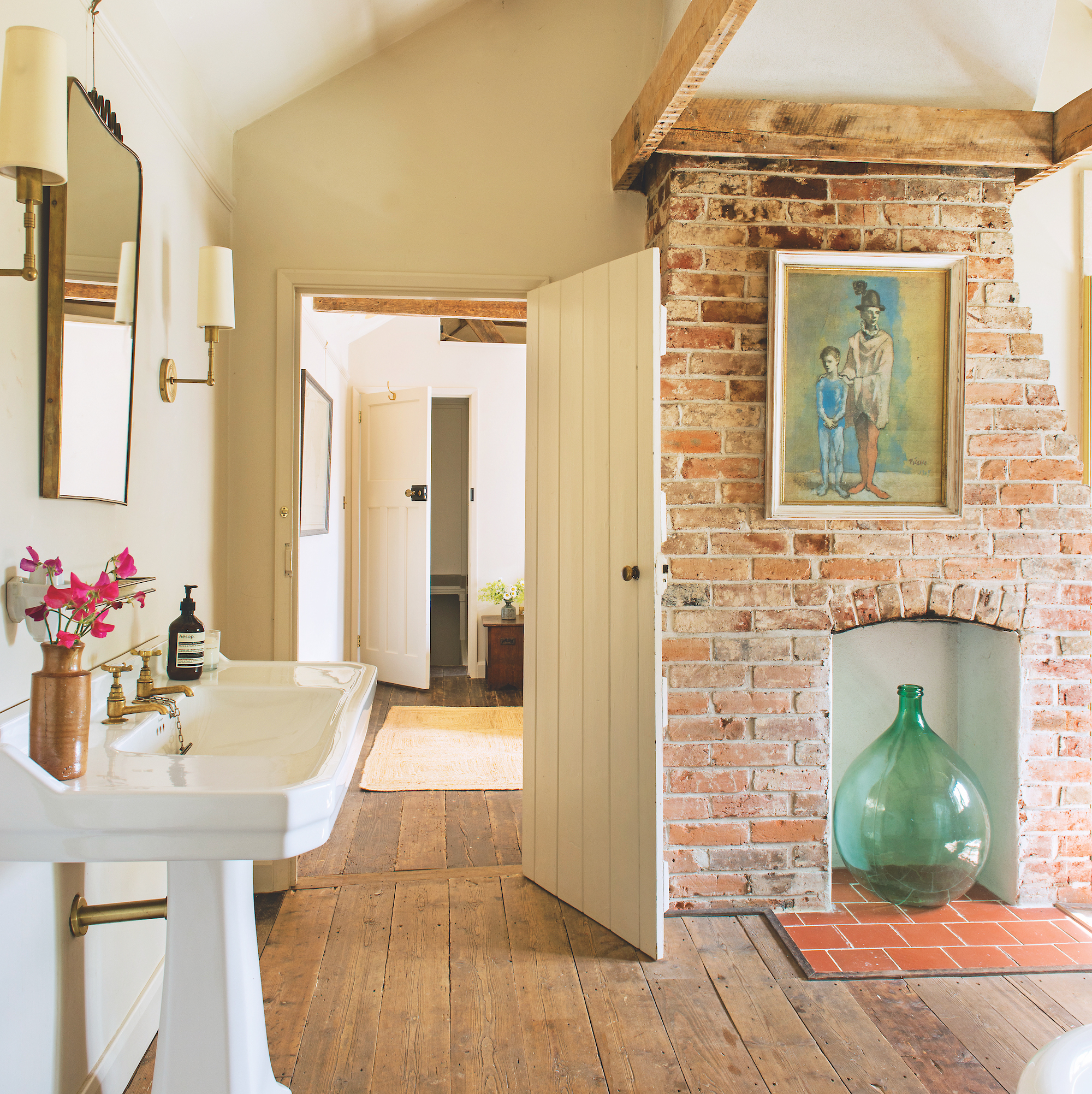 bathroom with exposed brick chimney breast and vintage style white pedestal sink and wooden floors