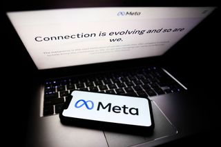 A smartphone lying on a laptop displaying the Meta company logo