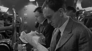 Black and white screenshot of Jonathon Price working at a desk in Brazil