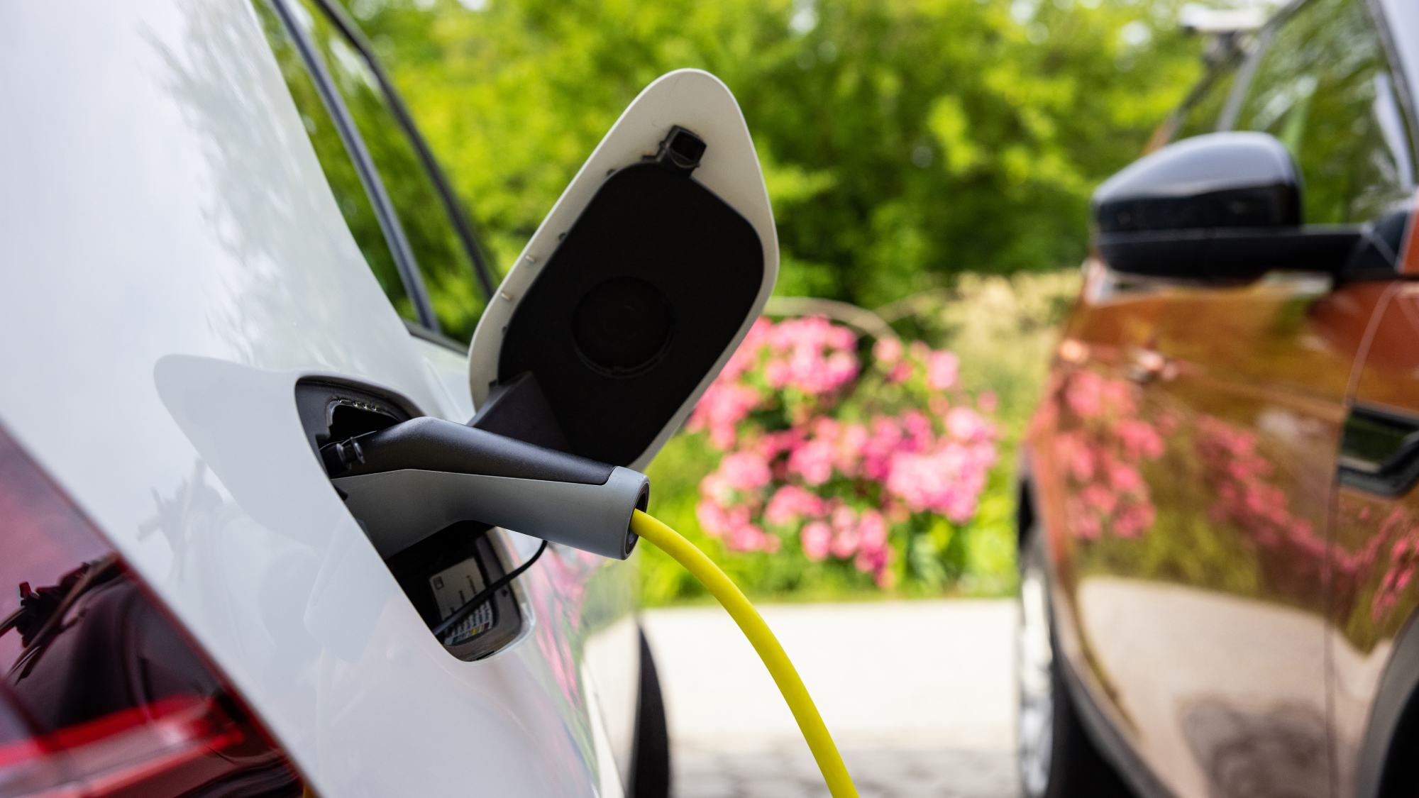 EV charger placed in white car with red car next to it