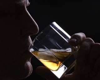 A man drinks a glass of alcohol