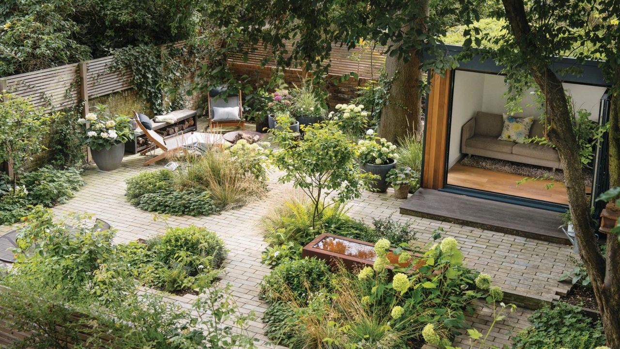  Birds eye view of the garden with a garden room, patio seating area, water feature and borders of green shrubs. Pub Orig Karen Howden and Tom Gandey&#039;s ground floor flat&#039;s garden in North London.