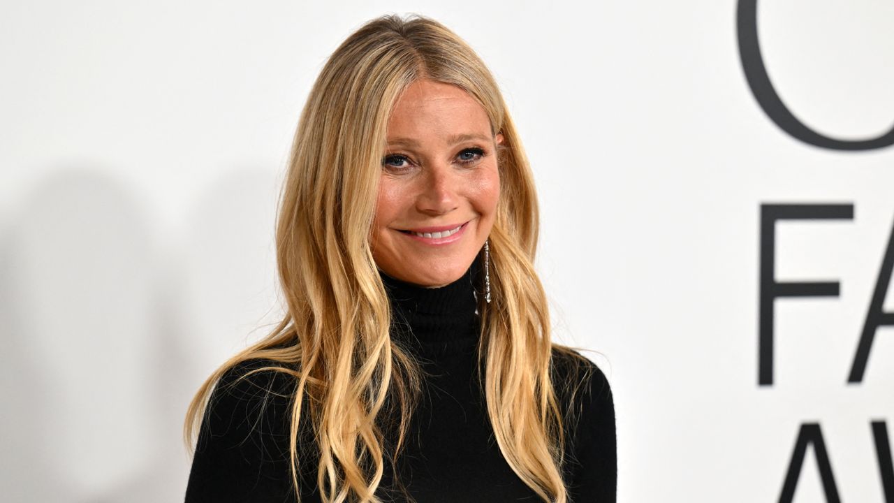 Image of Gywneth Paltrow in a black turtle neck long sleeve shirt standing in front of a white background