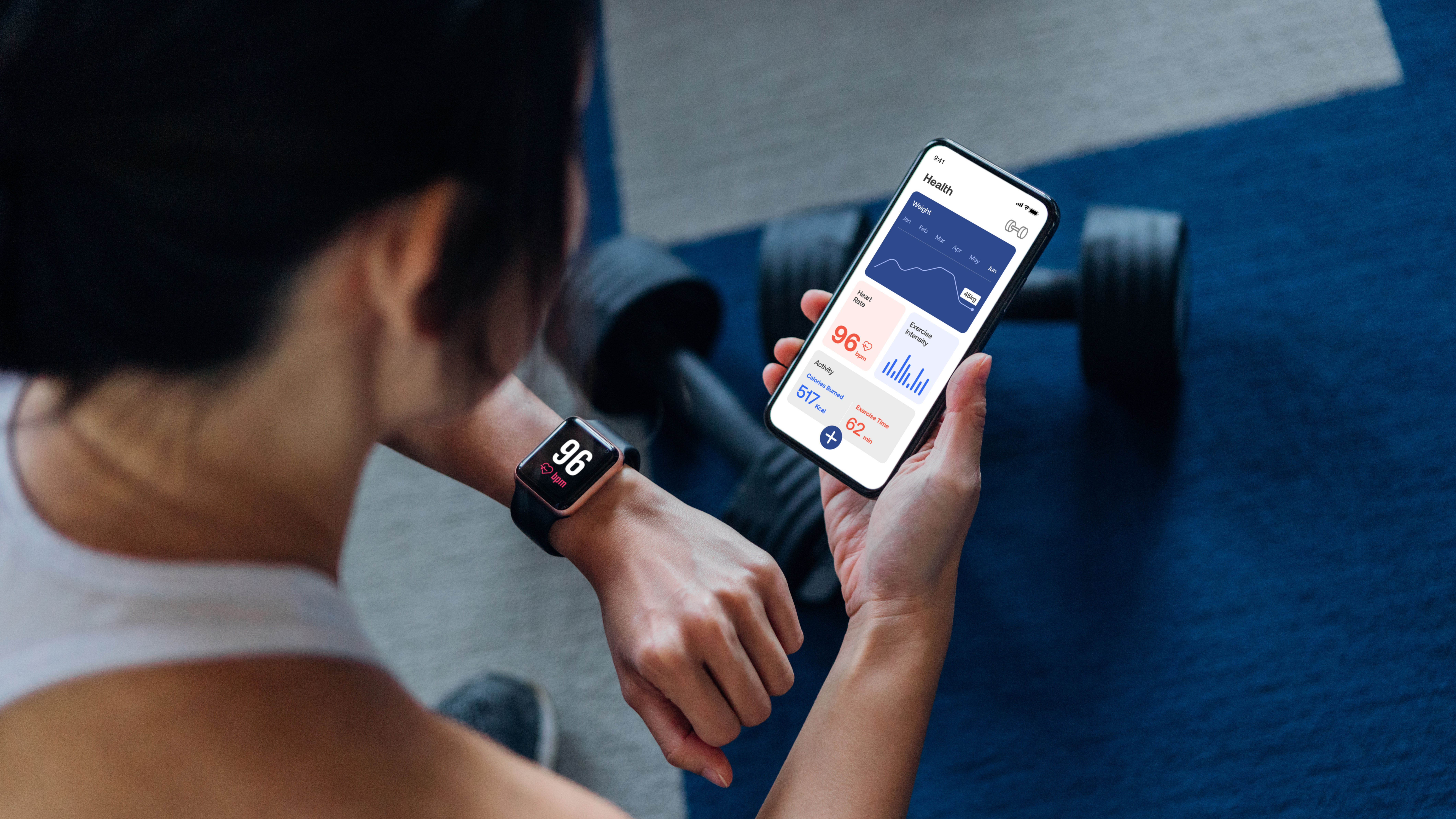 Woman looking at fitness tracker on wrist with dumbbells in background
