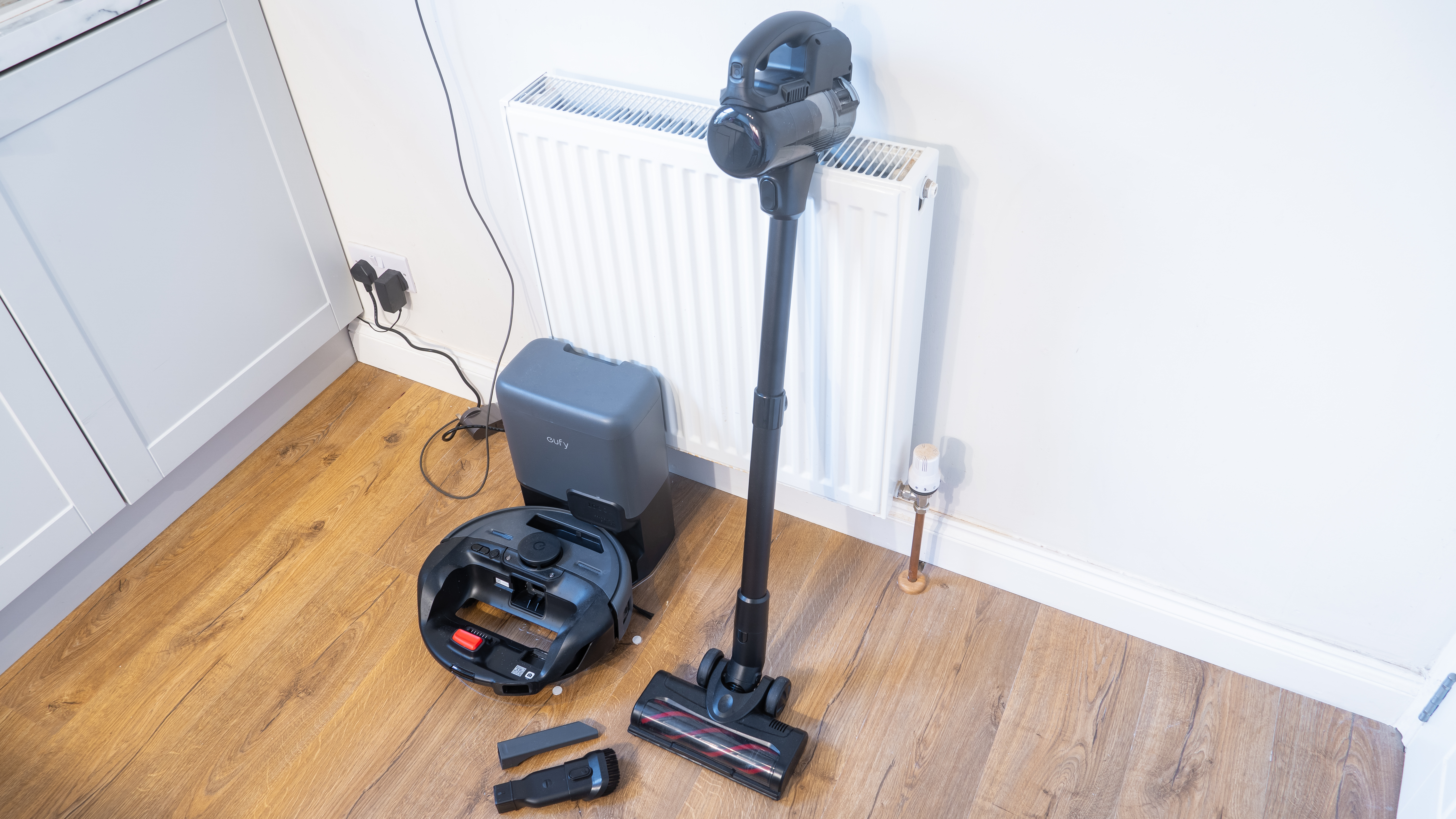 Eufy E20 robovac in dock, with manual vacuum and other accessories next to it