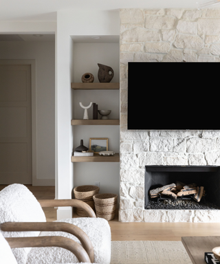 Exposed brick fireplace hearth with boucle chairs and open alcove shelving