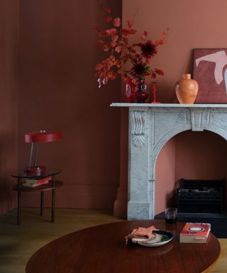 terracotta / coral living room with marble fire surround, coffee table, vase, artwork, side table