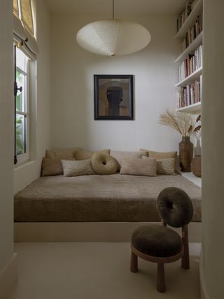 a deep window nook in brown fabric with a large paper lantern above