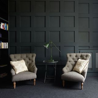 home library with panelled walls and grey armchairs