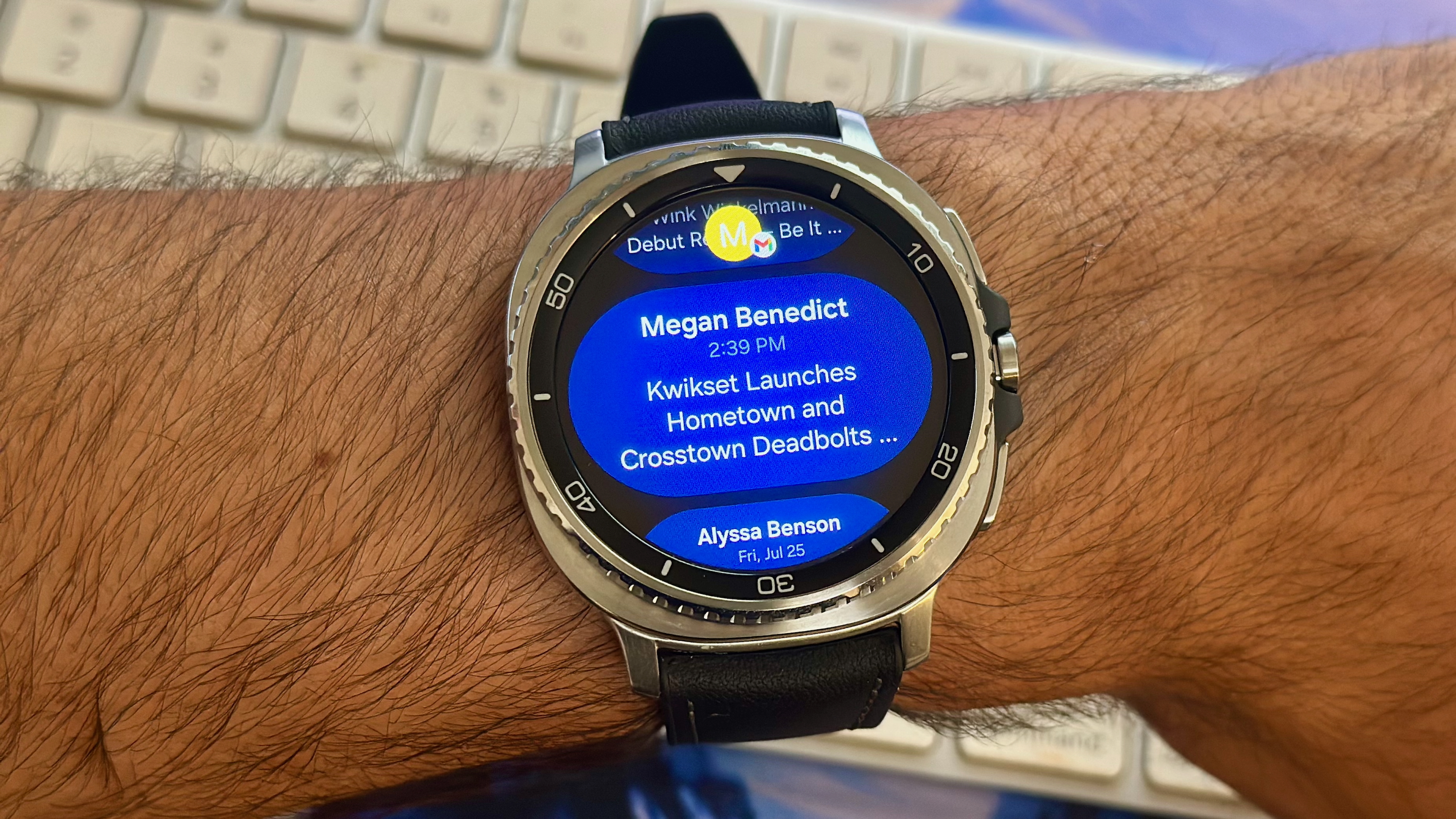 The Samsung Galaxy Watch 8 Classic showing Gmail notifications above a keyboard.