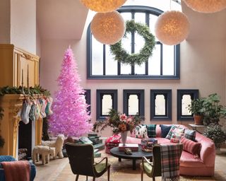 Large living room decorated with modern christmas decor, pink christmas tree and large wreath in window
