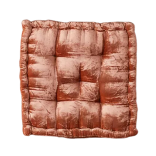 A velvet floor pillow in terracotta