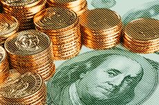 hundred dollar bill with stacks of gold coins on top