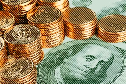 hundred dollar bill with stacks of gold coins on top