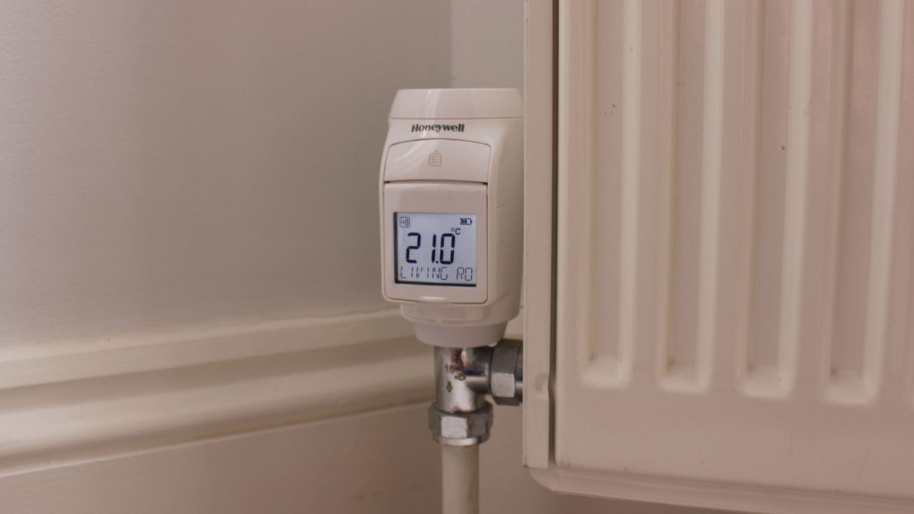 Honeywell Evohome smart radiator valve installed on a radiator, showing its relatively large size and bright screen