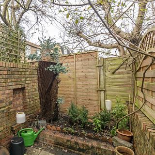 garden area with plants and trees with brick wall