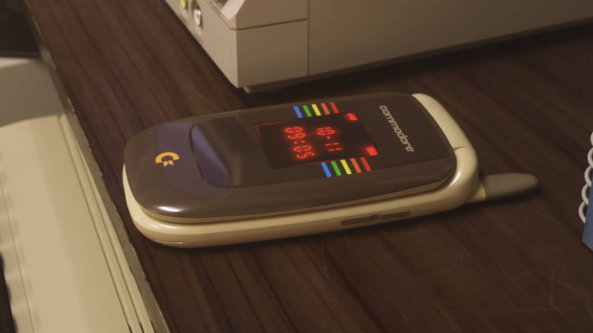 Commodore Callback 8020 flip-phone in beige sitting on woodgrain desk with clamshell closed.
