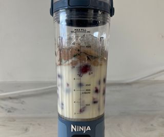 The ingredients of a protein shake before testing them in the Ninja Blast - frozen berries, oat milk, spinach, creatine, protein powder, and ice