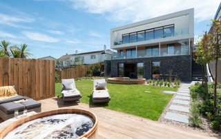 Three story property with decking and hot tub and lawn