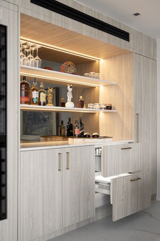 A corner cabinet holding spirits, with undercabinet lighting