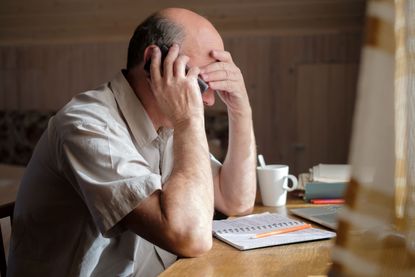 A man is on a telephone while looking stressed