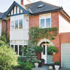 Exterior of red brick semi detached 1930s house with drive real home