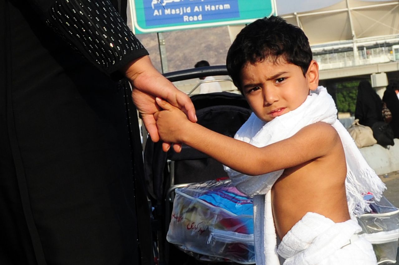 A little Muslim pilgrim boy holds his mother&amp;#039;s hand in Mina, five kilometres (three miles) east of the Saudi Arabian holy city of Mecca, on November 14, 2010, as some 2.5 million Muslim pilgr