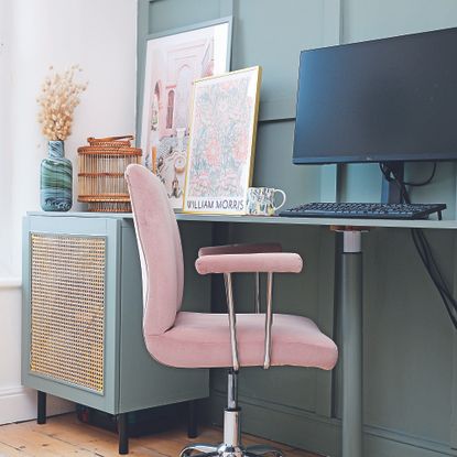 Home office with teal furniture, rattan cupboard and pink chair.