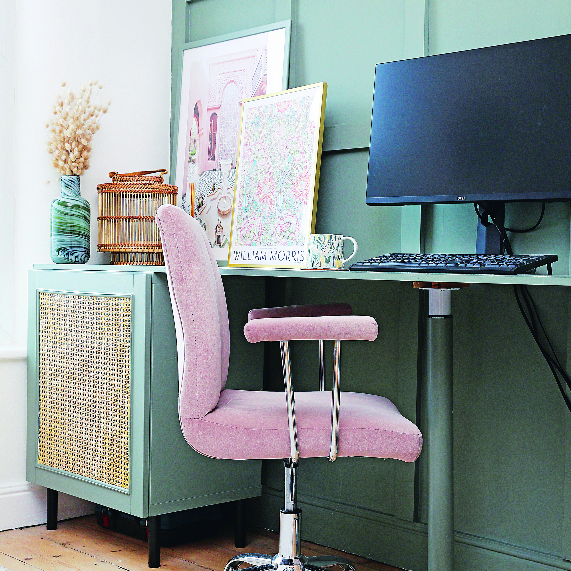 Home office with teal furniture, rattan cupboard and pink chair.