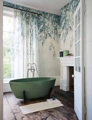 Bathroom with wood floor, green tub and botanical wallpaper